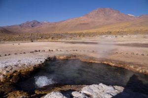 Hot springs in a sand-colored landscape with a mountain