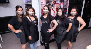 Group of women posing in a nail salon wearing masks